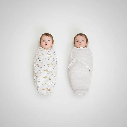Two babies wrapped in swaddles on a beige carpet